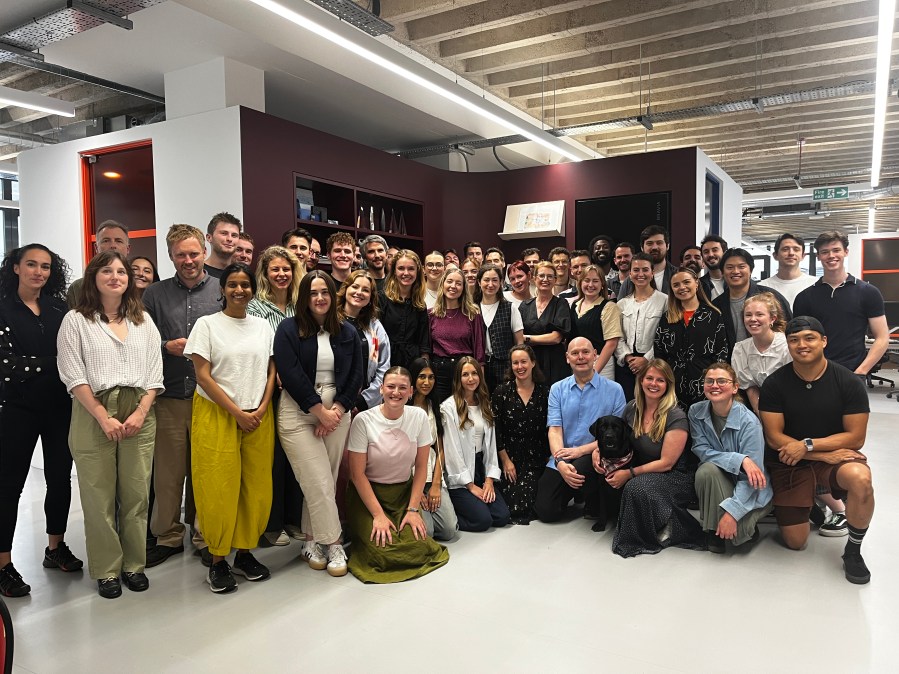 A group of people posing for a photo in an office environment, showcasing a diverse team of professionals.