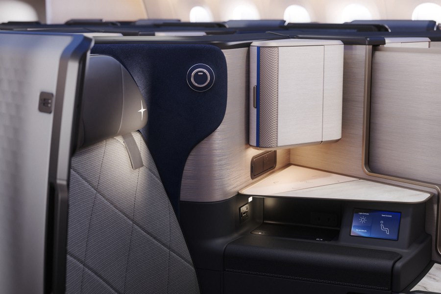 Close-up view of a premium airline seat featuring modern design elements, integrated controls, and ambient lighting.